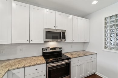 Kitchen with stainless steel appliances, tasteful backsplash, white cabinets, recessed lighting, and light granite countertops