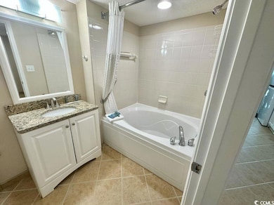 Full bathroom featuring shower / tub combo with curtain, vanity, tile patterned floors, and a textured ceiling
