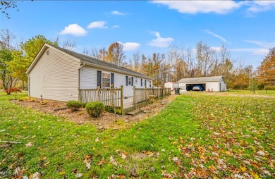 View of property exterior featuring an outbuilding, a yard, a detached garage, and a wooden deck