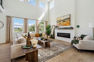 Living area featuring plenty of natural light, a high ceiling, light wood finished floors, and a glass covered fireplace