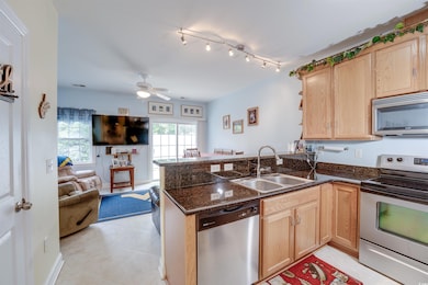 Kitchen featuring stainless steel appliances, a sink, light brown cabinets, open floor plan, and a peninsula