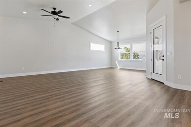 Unfurnished living room with a ceiling fan, a chandelier, lofted ceiling, dark wood-style flooring, and recessed lighting