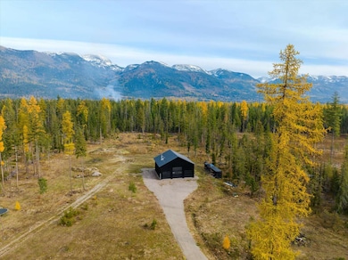 Aerial view of property and surrounding area with mountains and a forest