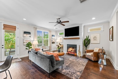 Living room featuring ornamental molding, ceiling fan, baseboards, a large fireplace, and dark wood-style floors