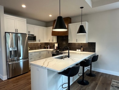 Kitchen featuring stainless steel appliances, a kitchen bar, decorative backsplash, white cabinetry, and recessed lighting