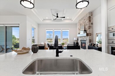 Kitchen with open floor plan, light stone counters, a ceiling fan, and a fireplace