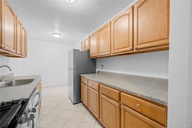 Kitchen featuring appliances with stainless steel finishes, light tile patterned floors, and light stone countertops