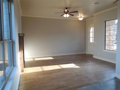 Empty room with crown molding, a ceiling fan, and dark wood-type flooring