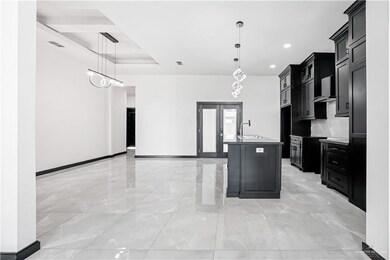 Kitchen with pendant lighting, sink, an island with sink, french doors, and wall chimney exhaust hood
