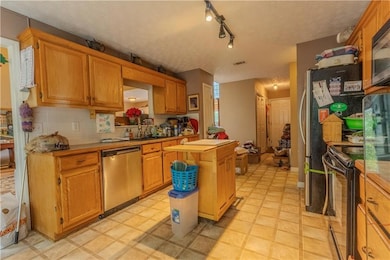 Kitchen with dishwasher, black range oven, a sink, a kitchen island, and light countertops
