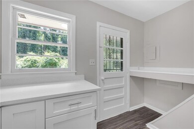 Doorway to outside featuring baseboards and dark wood-style floors
