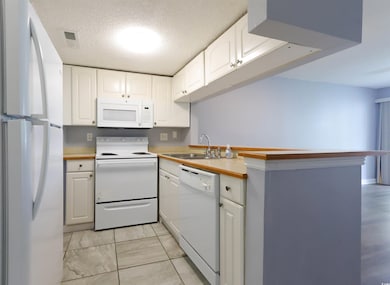 Kitchen featuring white appliances, a sink, white cabinets, light countertops, and light marble finish flooring