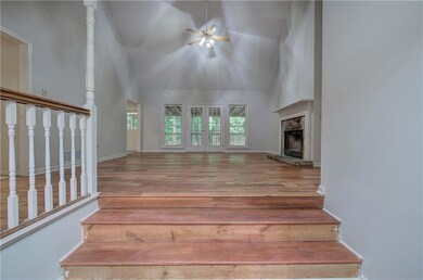 Unfurnished living room with high vaulted ceiling, a ceiling fan, wood finished floors, a high end fireplace, and baseboards