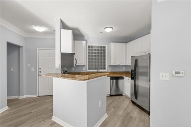 Kitchen featuring stainless steel appliances, dark stone countertops, white cabinetry, a peninsula, and light wood-style flooring