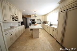 Kitchen featuring cream cabinets, light countertops, paneled built in refrigerator, a breakfast bar area, and a center island