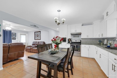 Kitchen featuring light tile patterned floors, appliances with stainless steel finishes, decorative backsplash, white cabinets, and recessed lighting