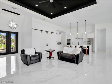 Living room featuring a tray ceiling, a towering ceiling, a barn door, light marble finish flooring, and recessed lighting
