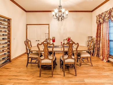 Dining room featuring a chandelier, light wood finished floors, crown molding, and baseboards