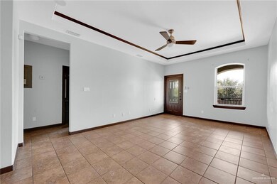 Spare room with a raised ceiling, a ceiling fan, baseboards, and light tile patterned floors
