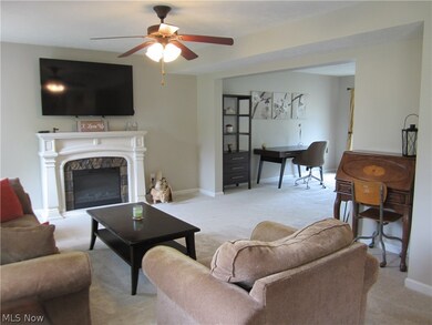 Living room with ceiling fan, carpet floors, and a tile fireplace