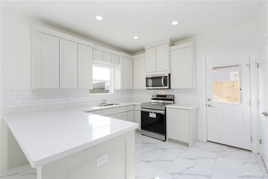 Kitchen with light countertops, stainless steel appliances, marble finish floor, a sink, and a peninsula