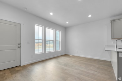 Unfurnished dining area featuring baseboards, recessed lighting, light wood-style flooring, and a sink