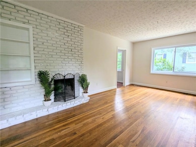 Unfurnished living room with wood finished floors, a fireplace, and a textured ceiling