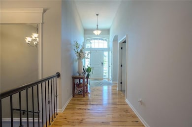 Hallway featuring light wood-style floors, a chandelier, and a high ceiling