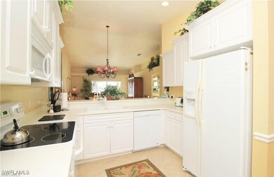 Kitchen with white cabinets, a notable chandelier, white appliances, and sink