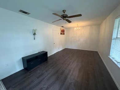 Unfurnished living room with a chandelier, dark wood-style flooring, ceiling fan, and baseboards