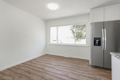 Kitchen featuring wood-type flooring, stainless steel refrigerator with ice dispenser, and white cabinets