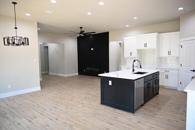 Kitchen with light hardwood / wood-style floors, sink, an island with sink, and white cabinets