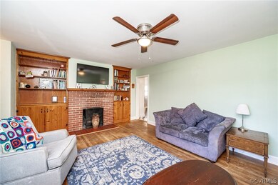 Living room with built in shelves, dark hardwood / wood-style floors, ceiling fan, and a fireplace