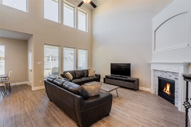 This living room is more like a GREAT room featuring a stunning fireplace with mantel detailing, custom paint, soaring high ceiling, dark stained ceiling fan, and an amazing wall of windows providing a lovely view of your backyard to keep an eye out on the kids or pets playing.