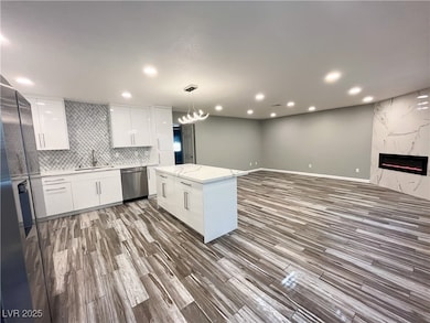 Kitchen featuring white cabinets, modern cabinets, decorative light fixtures, light stone counters, and recessed lighting