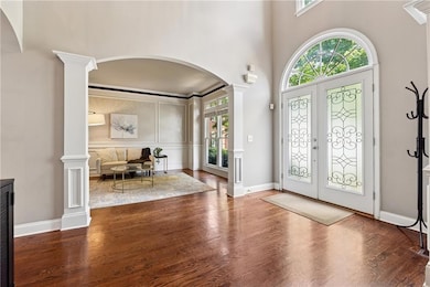 Foyer entrance featuring arched walkways, decorative columns, wood finished floors, and a decorative wall