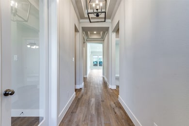 Corridor featuring wood finished floors, a chandelier, and ornamental molding