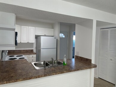Kitchen with white appliances, sink, a textured ce