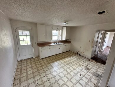 Kitchen featuring a textured ceiling, white cabine