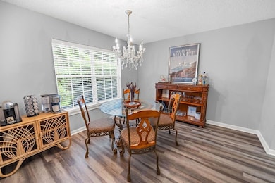 Dining room with a chandelier, wood finished floors, baseboards, and a textured ceiling