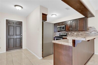 Kitchen featuring stainless steel appliances, backsplash, a peninsula, dark brown cabinets, and a breakfast bar area