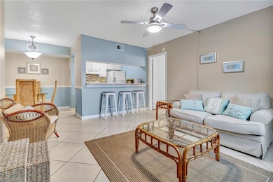 Living room featuring light tile patterned flooring, a textured ceiling, and ceiling fan
