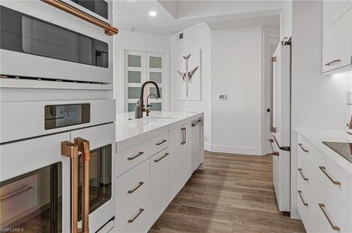 Kitchen with white cabinets, white appliances, lig