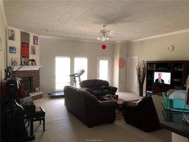 Living area with carpet floors, ceiling fan, ornamental molding, and a fireplace