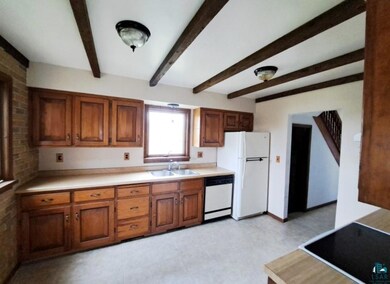 Kitchen featuring brick wall, beamed ceiling, sink