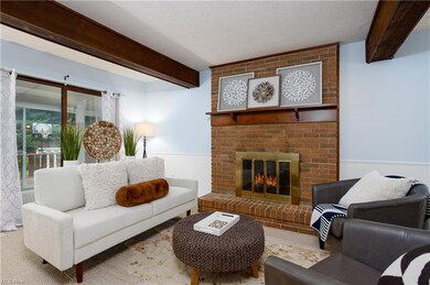Living room with brick wall, beam ceiling, a firep