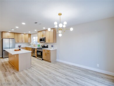 Kitchen featuring appliances with stainless steel finishes, light brown cabinets, a chandelier, light wood-type flooring, and recessed lighting