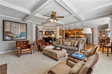 Living area with decorative columns, crown molding, beam ceiling, coffered ceiling, and light colored carpet