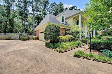 View of side of property with concrete driveway, brick siding, a garage, and roof with shingles