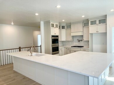 Kitchen featuring decorative backsplash, white cabinets, light stone countertops, recessed lighting, and glass insert cabinets